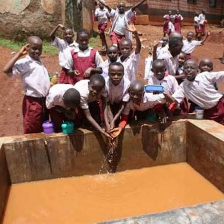 School children gathered around a basin of brown, untreated water